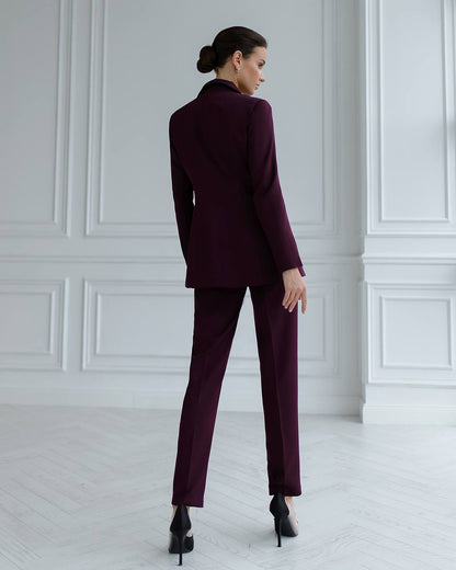 a woman in a purple suit stands in a white room