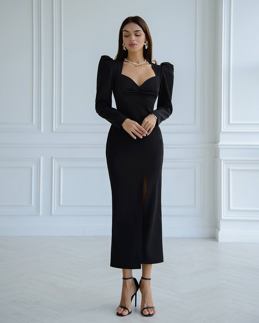 a woman in a black dress standing in a white room