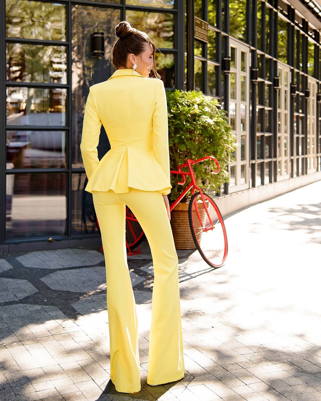 a woman in a yellow suit standing on a sidewalk
