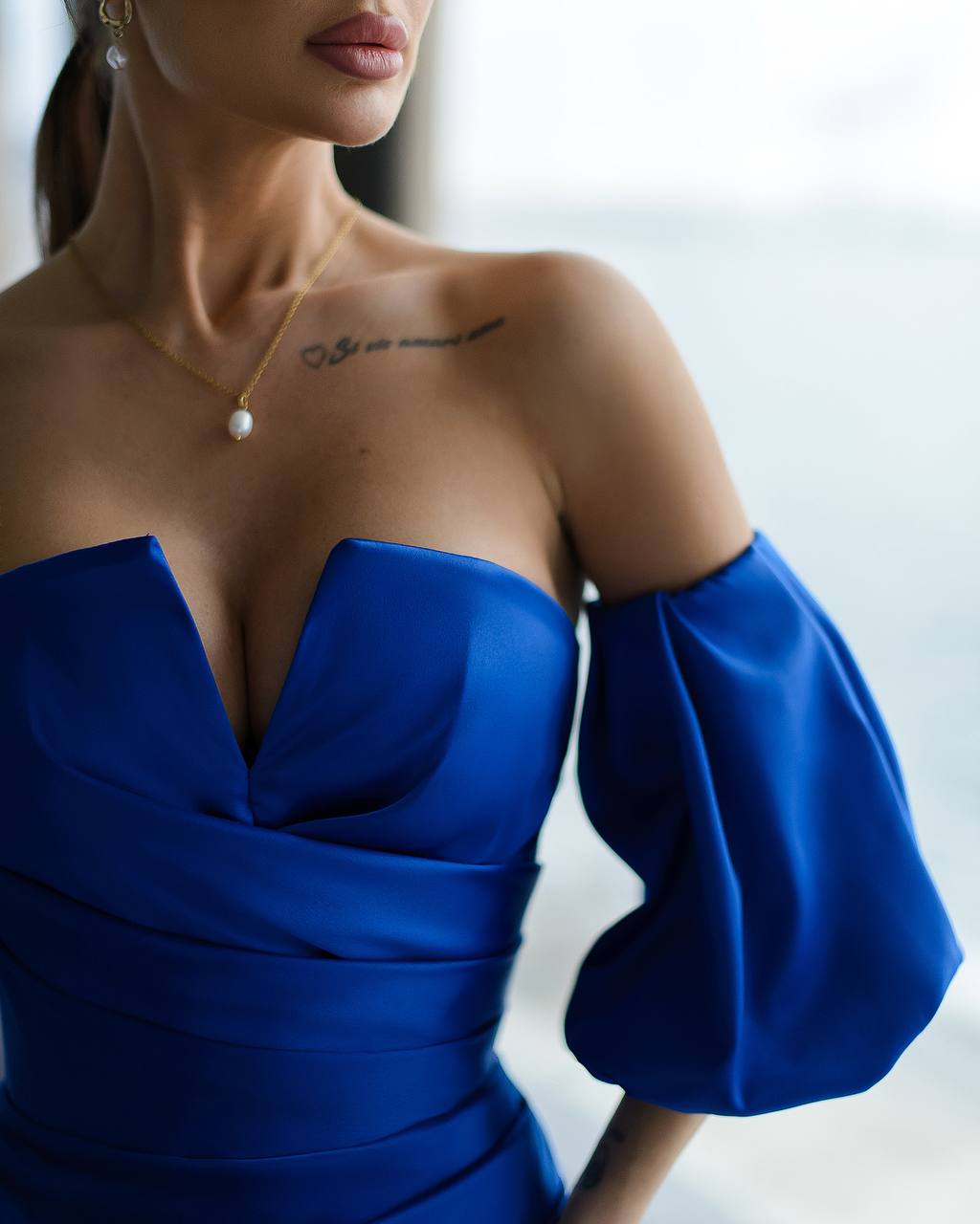 a woman wearing a blue dress and a pearl necklace