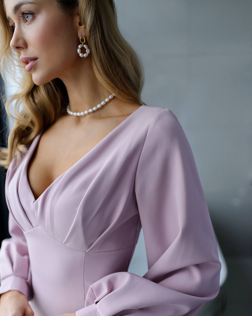 a woman in a pink dress with a pearl necklace