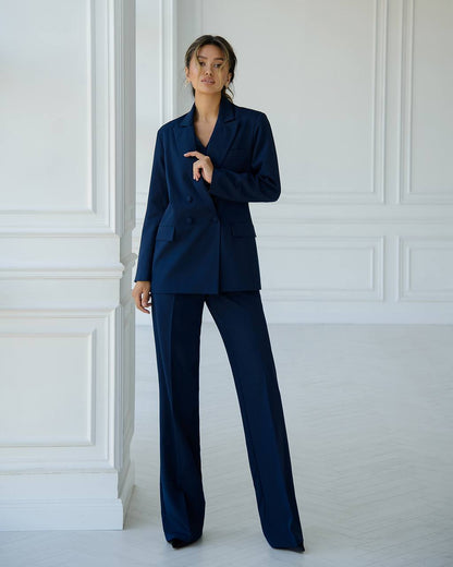 a woman in a blue suit leaning against a wall