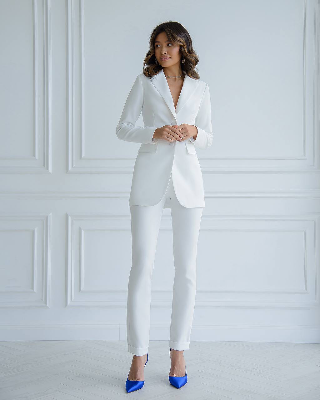 a woman wearing a white suit and blue shoes