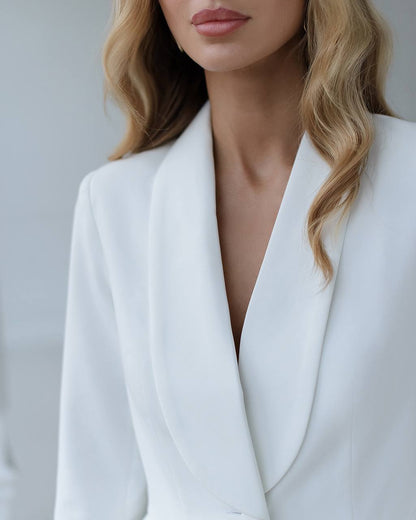 a woman wearing a white suit and glasses