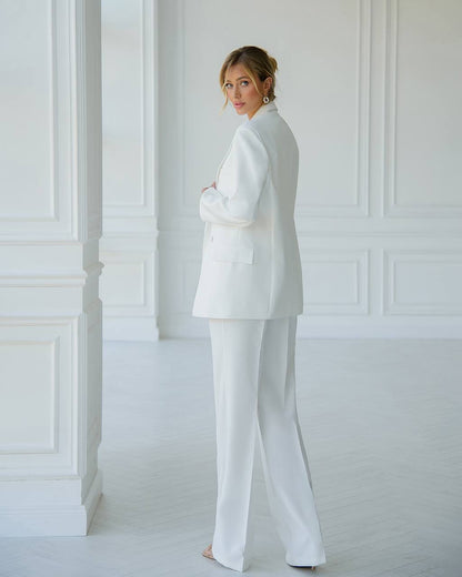 a woman in a white suit standing in a white room