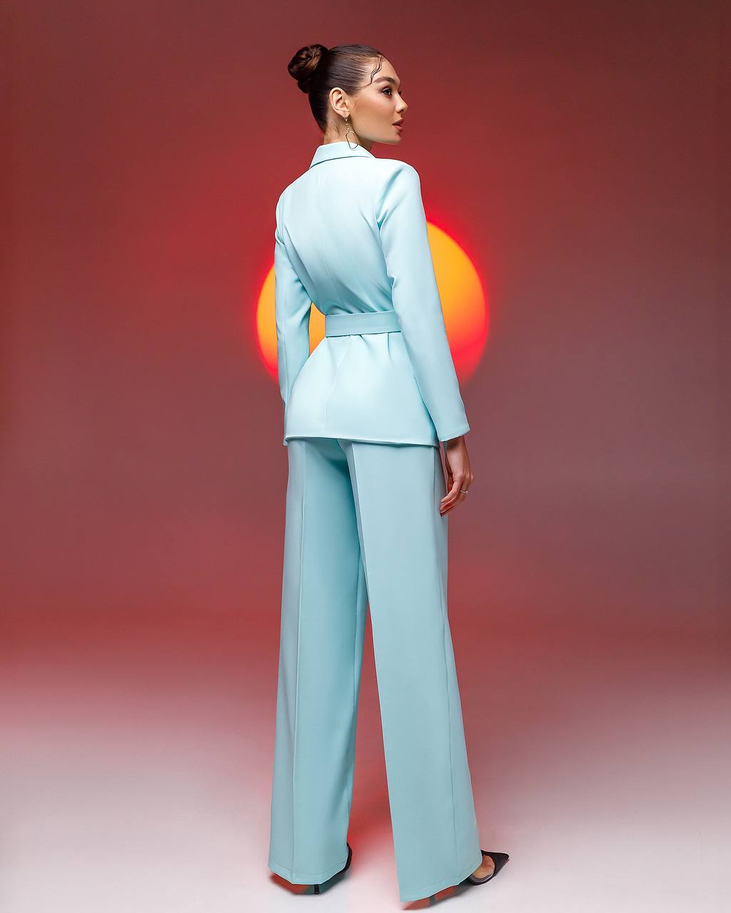 a woman in a light blue suit standing in front of a red background