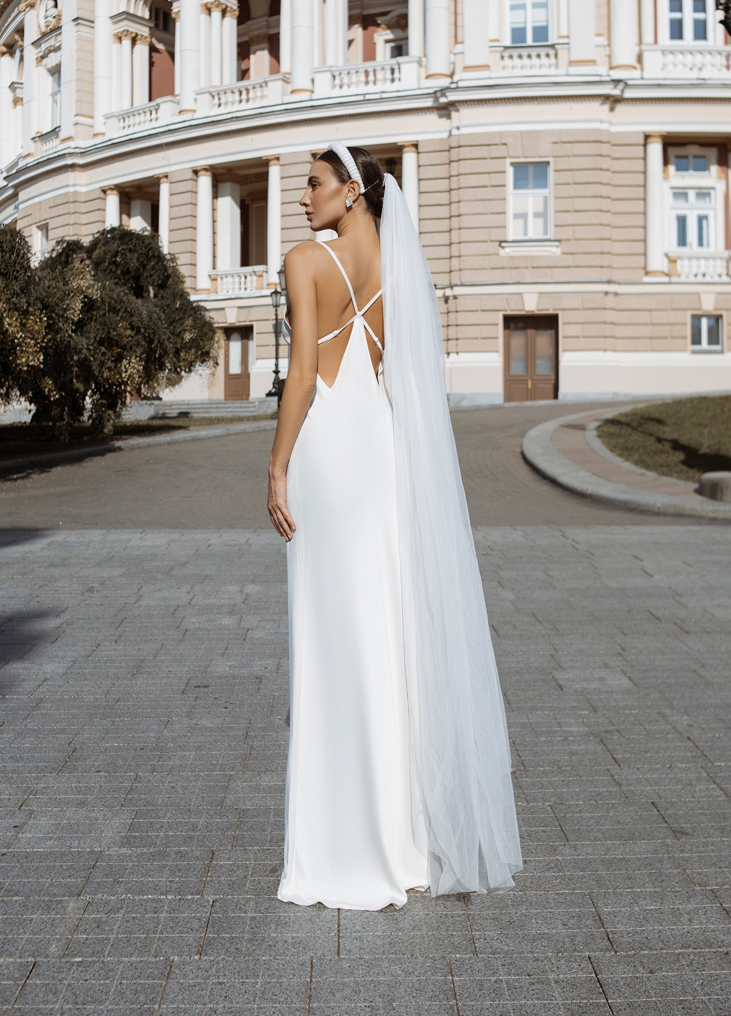 a woman in a white wedding dress is standing outside