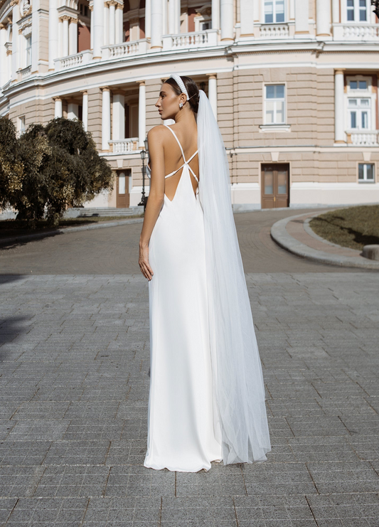a woman in a white wedding dress is standing outside
