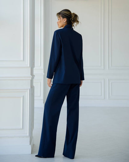 a woman in a blue suit stands in a white room