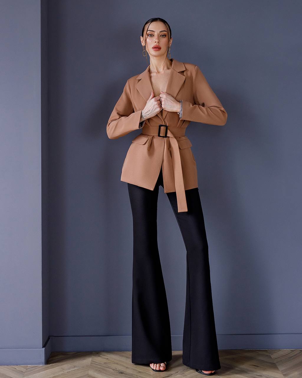a woman in a tan coat and black pants