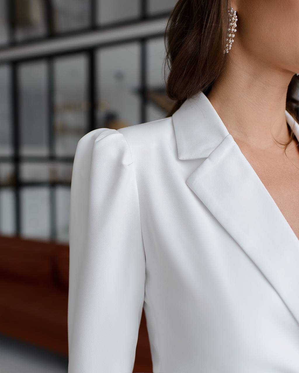 a woman wearing a white suit and earrings