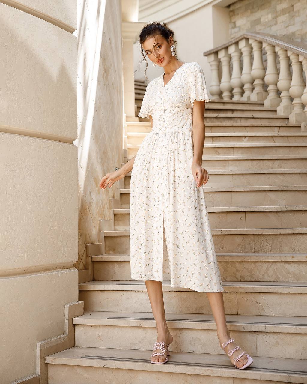 a woman in a white dress standing on a set of stairs