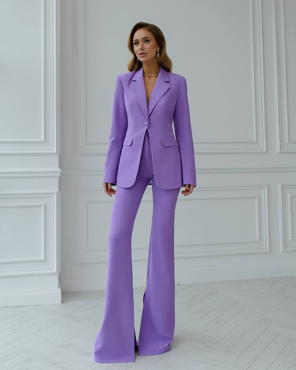 a woman in a purple suit stands in a white room