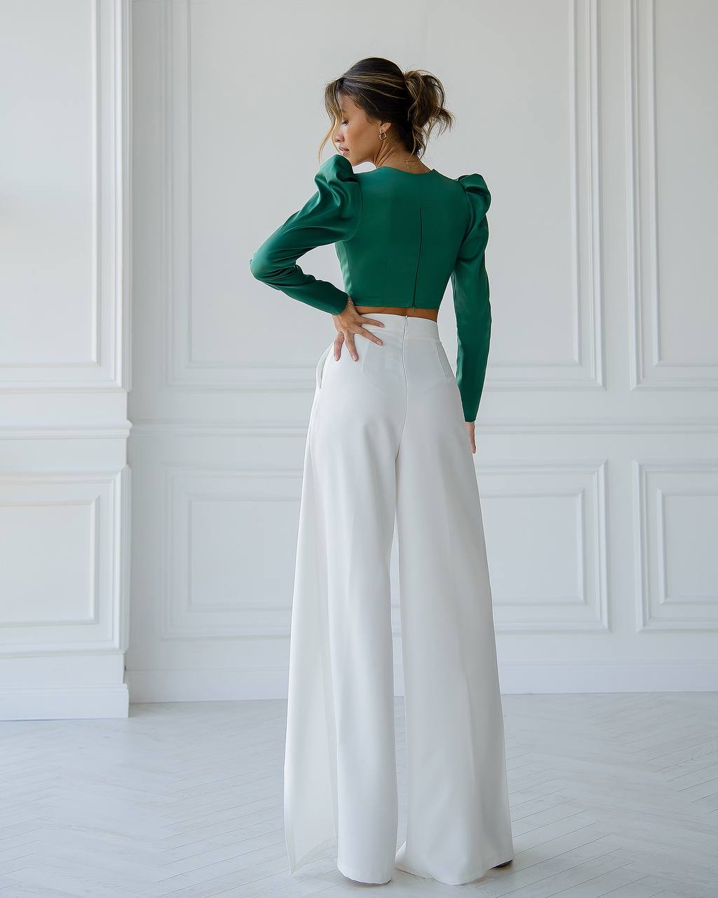 a woman in a green top and white pants